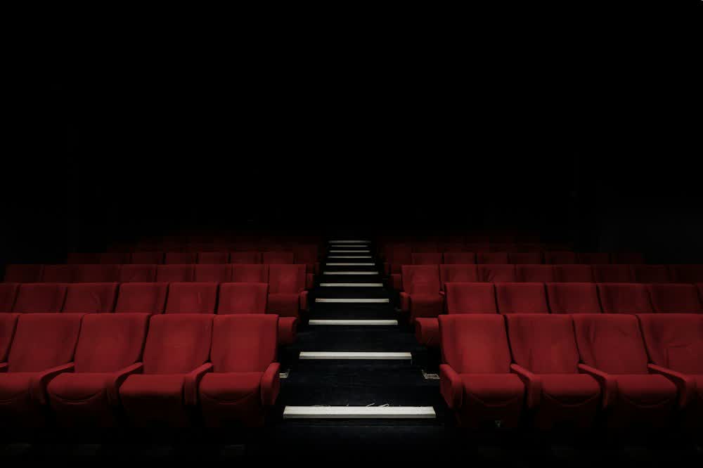 Rows of red cinema seats under a dark screen