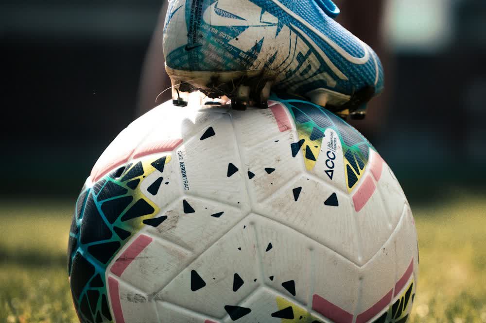 Two footballs stacked on a pitch